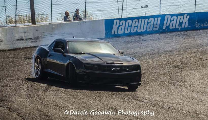 Front three-quarter of the Camaro mid-slide along the Raceway Park wall.