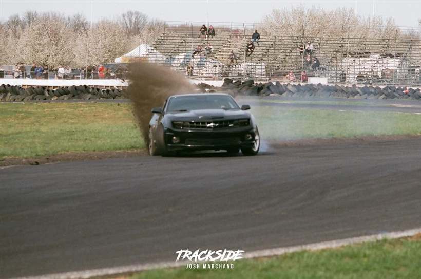 The Camaro throwing dirt off the outside of a corner with a full grandstand watching.